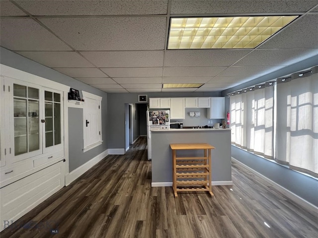 kitchen featuring a drop ceiling, white cabinets, and dark hardwood / wood-style flooring