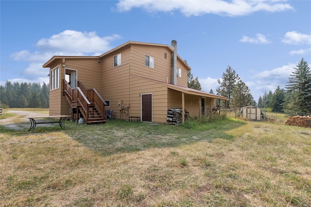 rear view of property with a lawn and a storage unit