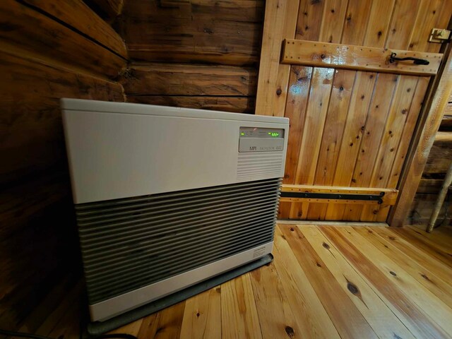 details featuring hardwood / wood-style flooring, heating unit, and wood walls