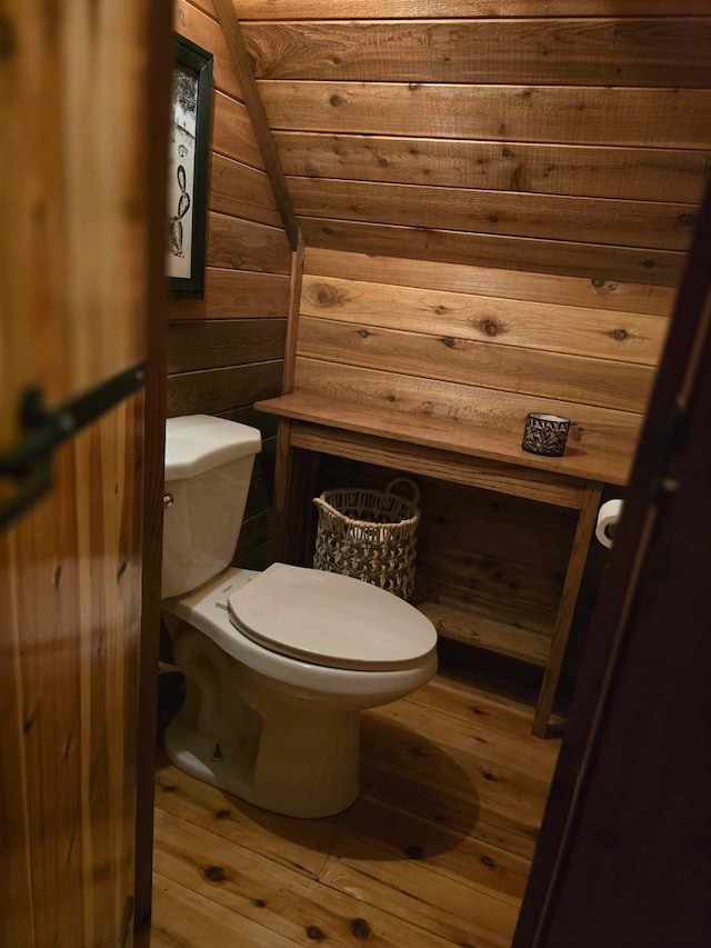 bathroom with toilet, wood walls, and hardwood / wood-style floors