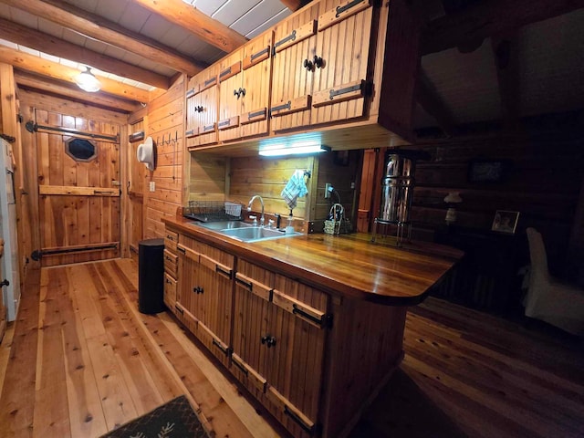 kitchen with wooden ceiling, light hardwood / wood-style floors, beamed ceiling, sink, and kitchen peninsula