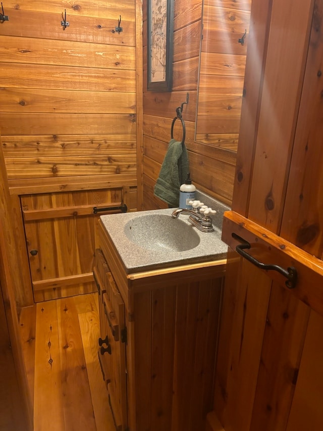 bathroom with vanity, hardwood / wood-style floors, and wooden walls