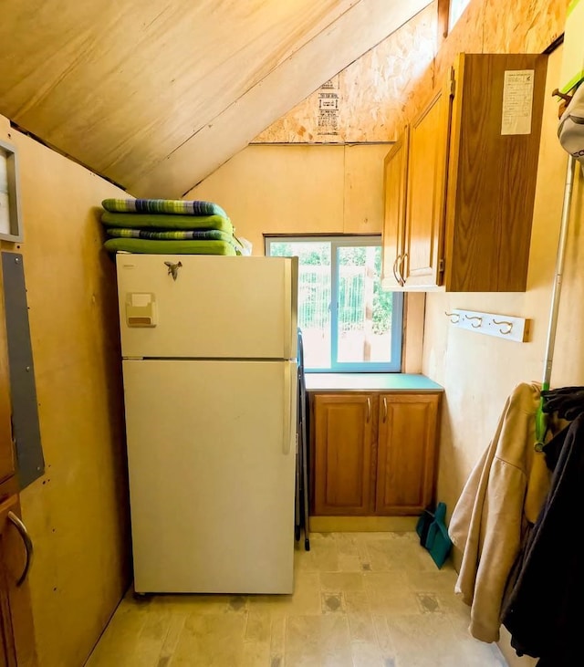 kitchen featuring lofted ceiling and white fridge