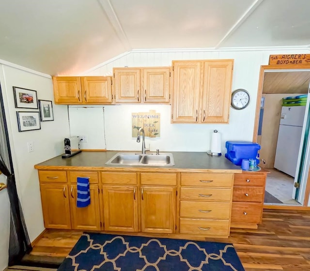 kitchen featuring white fridge, hardwood / wood-style flooring, vaulted ceiling, and sink