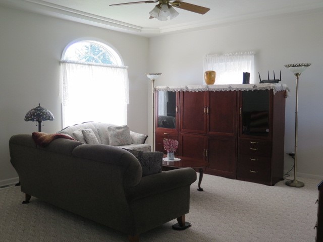 living room with light carpet, crown molding, and ceiling fan