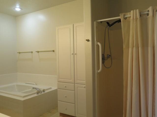 full bathroom featuring a shower stall and a garden tub