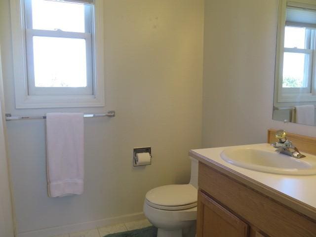 bathroom featuring toilet, tile patterned floors, vanity, and baseboards