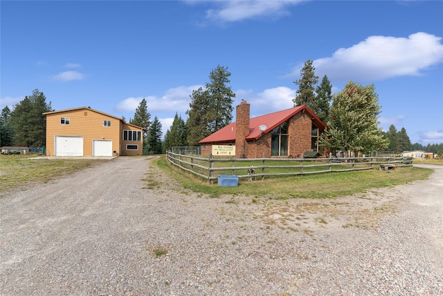 view of front of home with gravel driveway, fence, and a garage