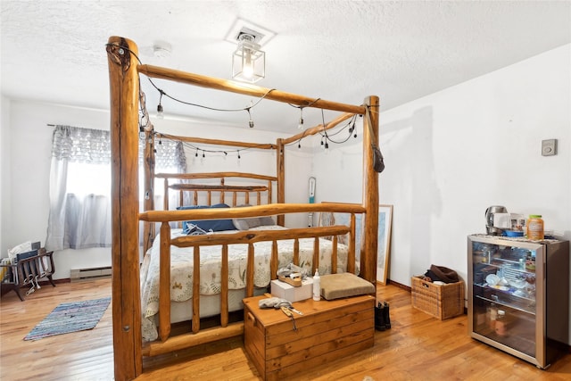 bedroom featuring beverage cooler, a baseboard radiator, a textured ceiling, and wood finished floors