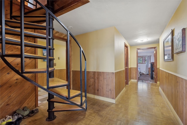 corridor featuring wood walls and light parquet floors