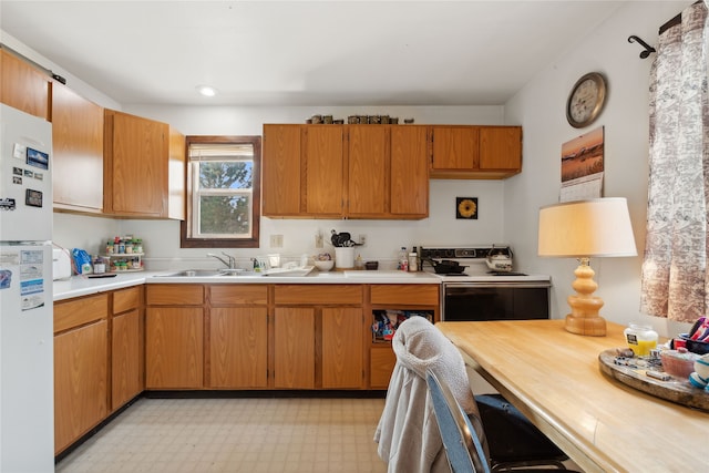 kitchen featuring stainless steel electric range oven, white refrigerator, and sink