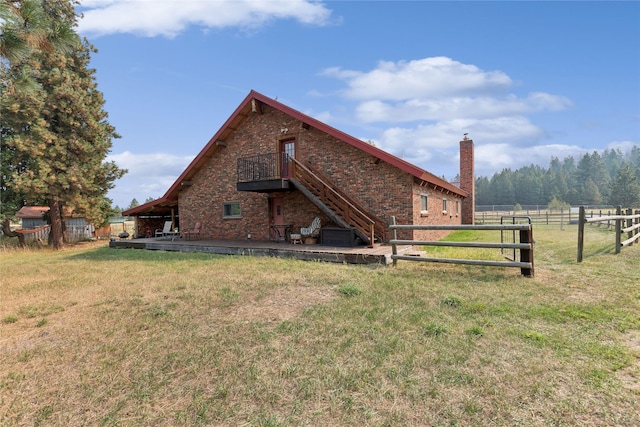 rear view of house featuring fence, stairway, a lawn, a chimney, and a deck