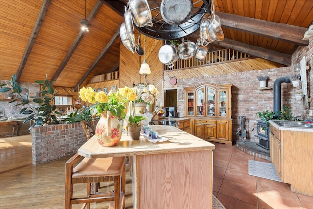 kitchen featuring beamed ceiling, wooden ceiling, a wood stove, high vaulted ceiling, and light wood-type flooring