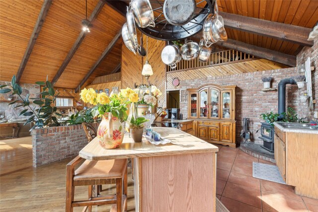 kitchen featuring light countertops, beam ceiling, wooden ceiling, a wood stove, and high vaulted ceiling