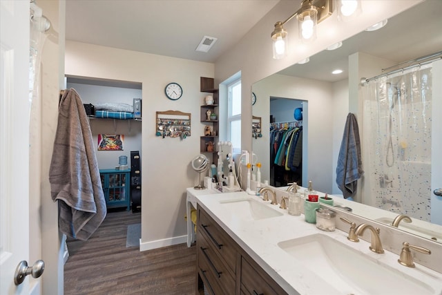 full bathroom with a sink, baseboards, wood finished floors, and visible vents