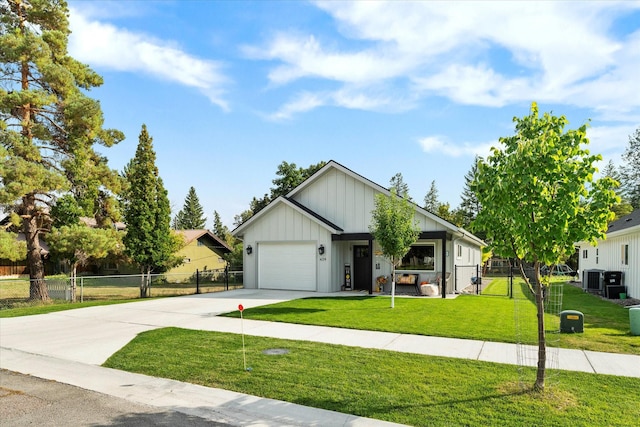 view of front of house with a garage, central AC, and a front lawn