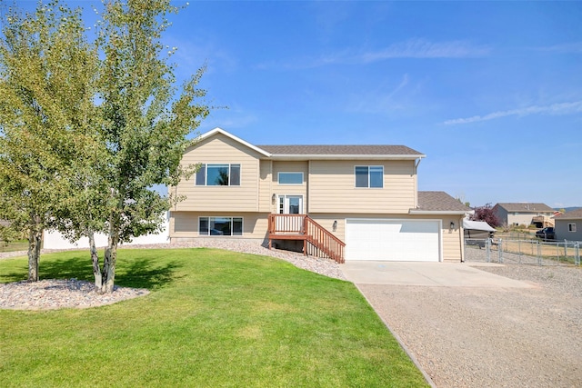 split foyer home featuring driveway, an attached garage, a front lawn, and fence