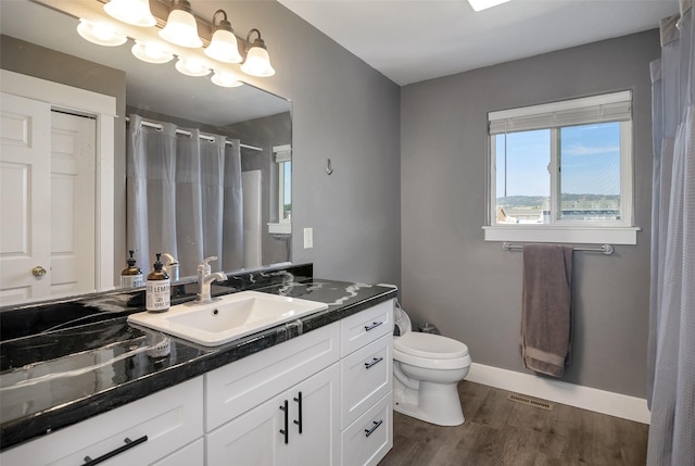 bathroom featuring vanity, wood finished floors, visible vents, baseboards, and toilet