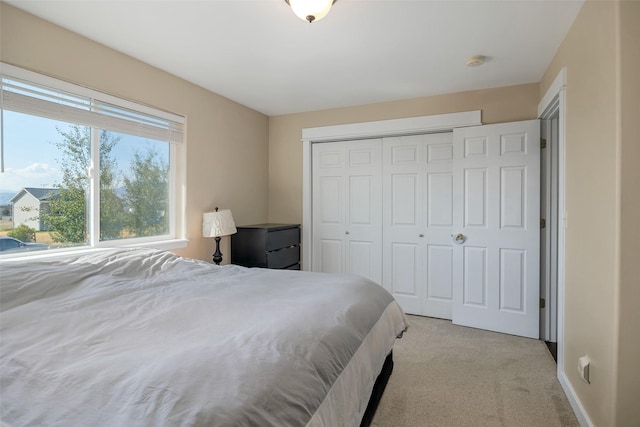 bedroom with baseboards, a closet, and light carpet