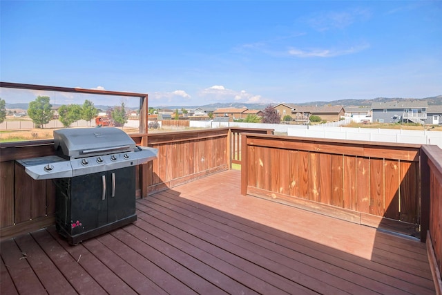 wooden terrace featuring a mountain view, a grill, a residential view, and fence