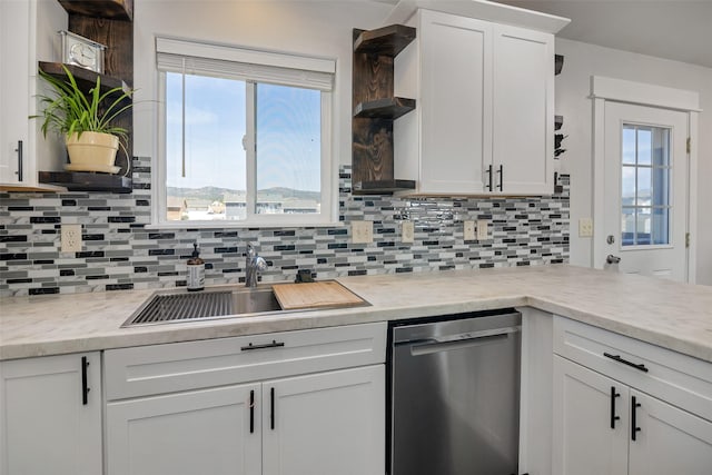 kitchen featuring backsplash, dishwasher, light countertops, white cabinets, and a sink