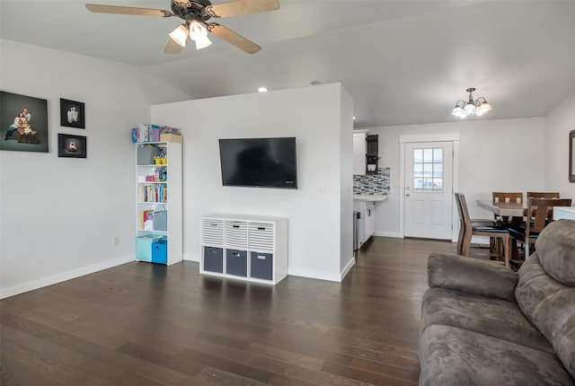 living area with baseboards, lofted ceiling, dark wood-style flooring, and ceiling fan with notable chandelier