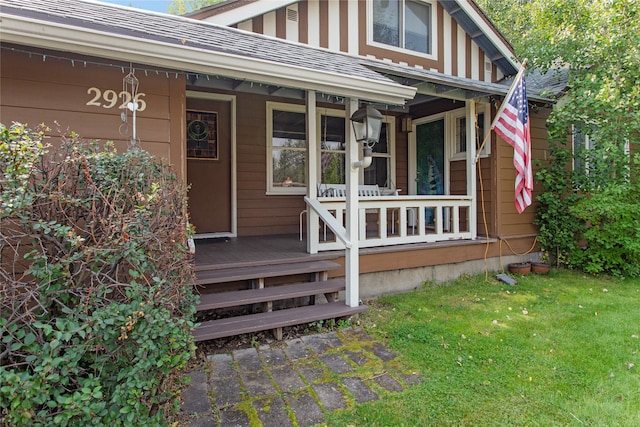 view of exterior entry featuring a lawn and covered porch