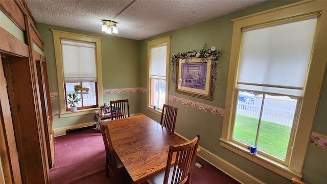 dining area featuring dark carpet, a textured ceiling, and a healthy amount of sunlight