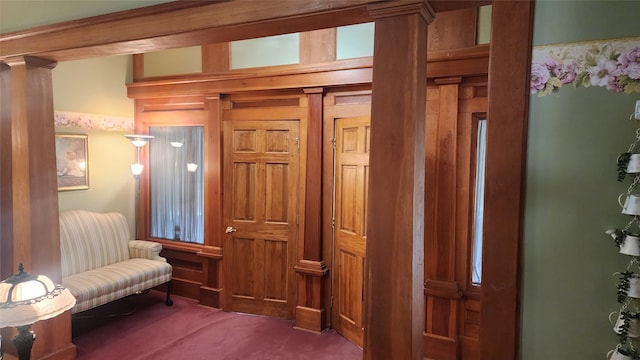 living area with dark carpet, beam ceiling, and ornate columns