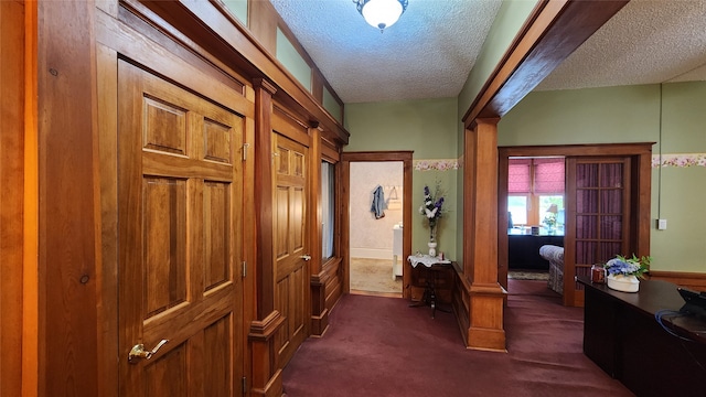 corridor featuring a textured ceiling and dark colored carpet