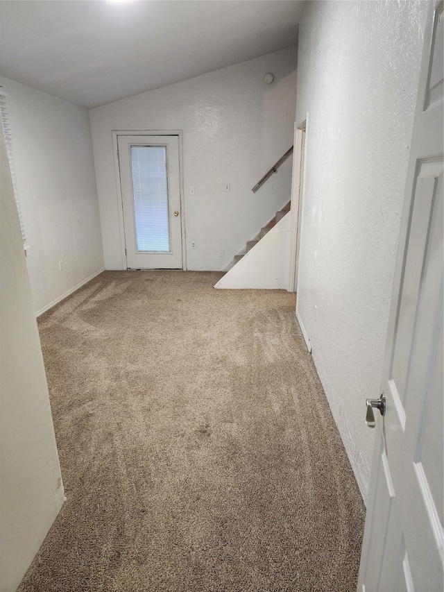 spare room featuring light carpet and vaulted ceiling