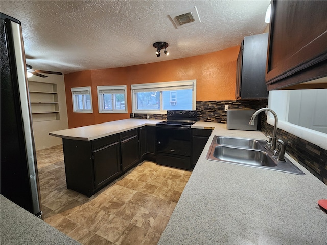 kitchen featuring kitchen peninsula, backsplash, sink, black electric range, and a textured ceiling