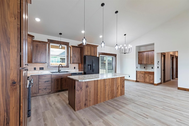 kitchen featuring a sink, light wood-style flooring, a kitchen island, and black fridge