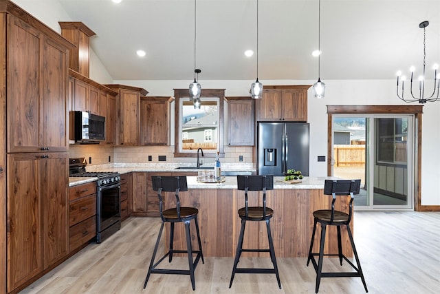 kitchen with lofted ceiling, a sink, appliances with stainless steel finishes, a center island, and tasteful backsplash