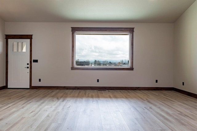 spare room featuring baseboards and wood finished floors