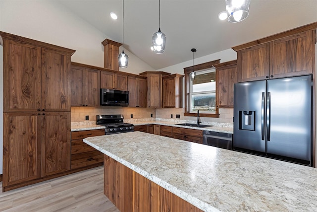 kitchen featuring stainless steel appliances, tasteful backsplash, hanging light fixtures, vaulted ceiling, and a sink