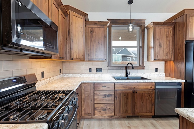 kitchen featuring light wood finished floors, decorative backsplash, brown cabinets, stainless steel appliances, and a sink