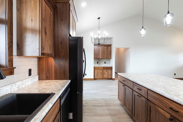 kitchen with decorative light fixtures, light countertops, light wood-style flooring, freestanding refrigerator, and a sink