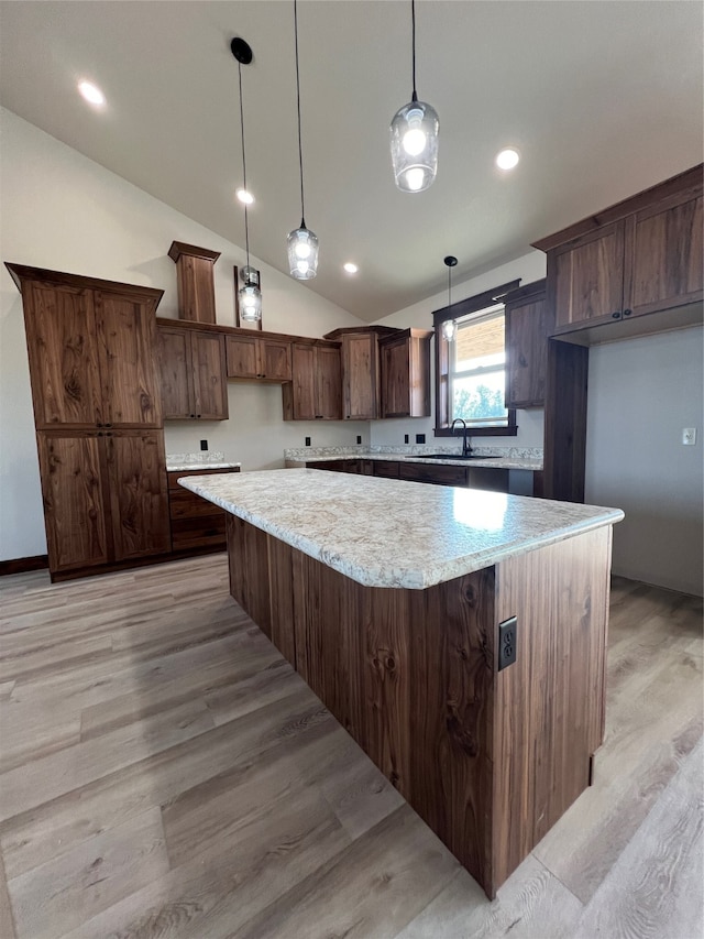 kitchen with light hardwood / wood-style flooring, hanging light fixtures, a large island, and vaulted ceiling