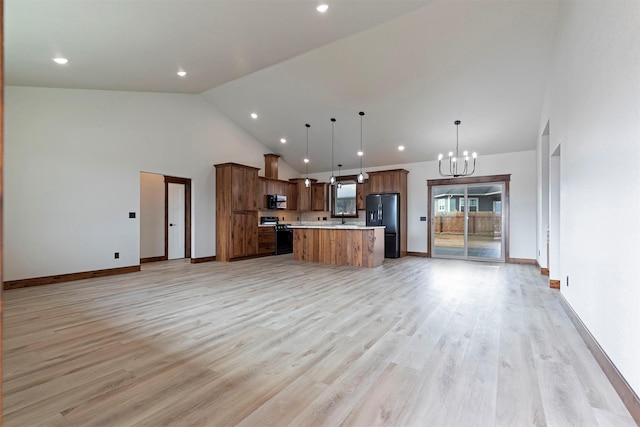 kitchen featuring a kitchen island, open floor plan, an inviting chandelier, light countertops, and black appliances