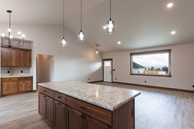 kitchen with decorative backsplash, a center island, hanging light fixtures, and light wood finished floors