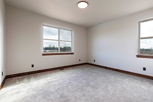 spare room featuring carpet floors, plenty of natural light, and baseboards