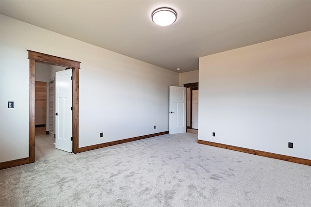 unfurnished room featuring light colored carpet and baseboards