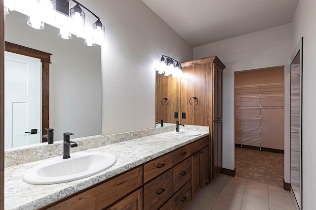 bathroom featuring double vanity, a spacious closet, tile patterned flooring, and a sink