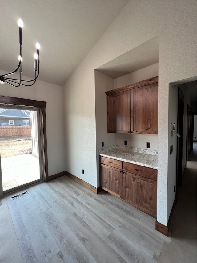 kitchen featuring lofted ceiling, light hardwood / wood-style floors, and a chandelier