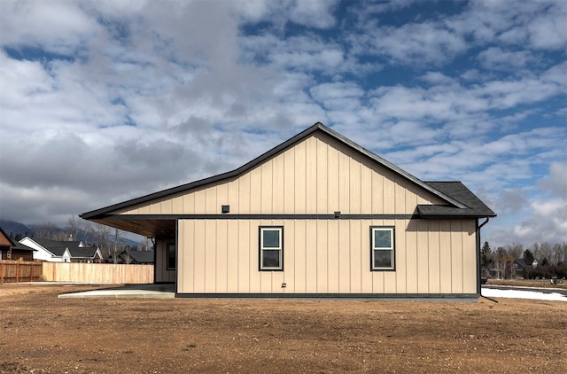 view of property exterior featuring a shingled roof, fence, and board and batten siding