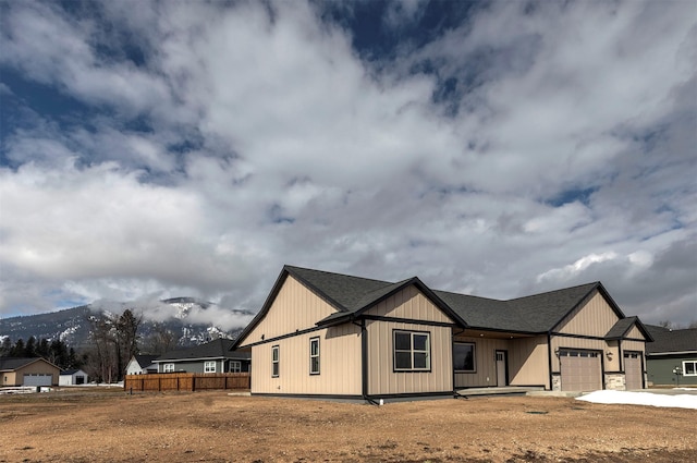 view of front of home with driveway, roof with shingles, an attached garage, and fence