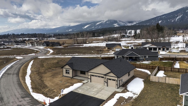 snowy aerial view featuring a residential view and a mountain view