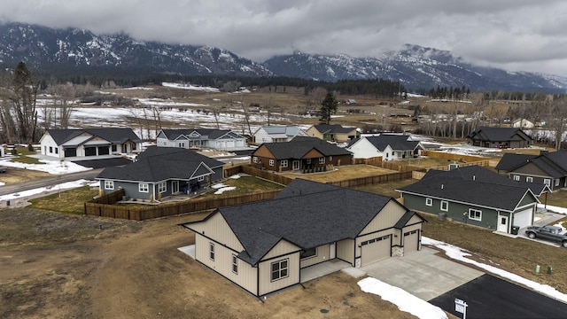 snowy aerial view featuring a mountain view and a residential view