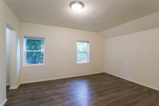 unfurnished room with lofted ceiling, dark hardwood / wood-style floors, and a textured ceiling